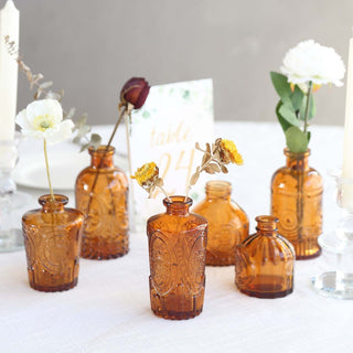 Vintage amber glass vases with flowers on a table setting.