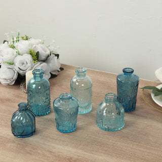 Decorative glass vases in various blue shades on a wooden surface.