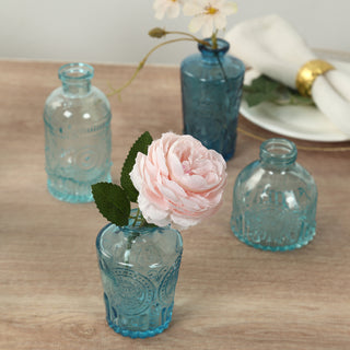 Set of vintage blue glass vases with flowers on a wooden surface.
