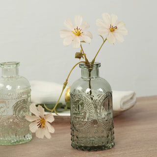 Vintage glass vase with delicate flowers arranged on a wooden table.