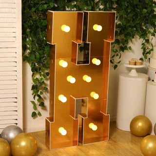 Gold marquee letter "H" with lights, styled in a festive setting.