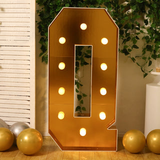 Gold marquee number 0 with lights against greenery and balloons.