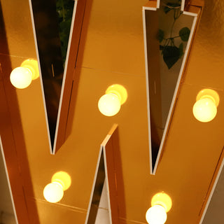Gold marquee letter "W" with bright bulbs illuminated.