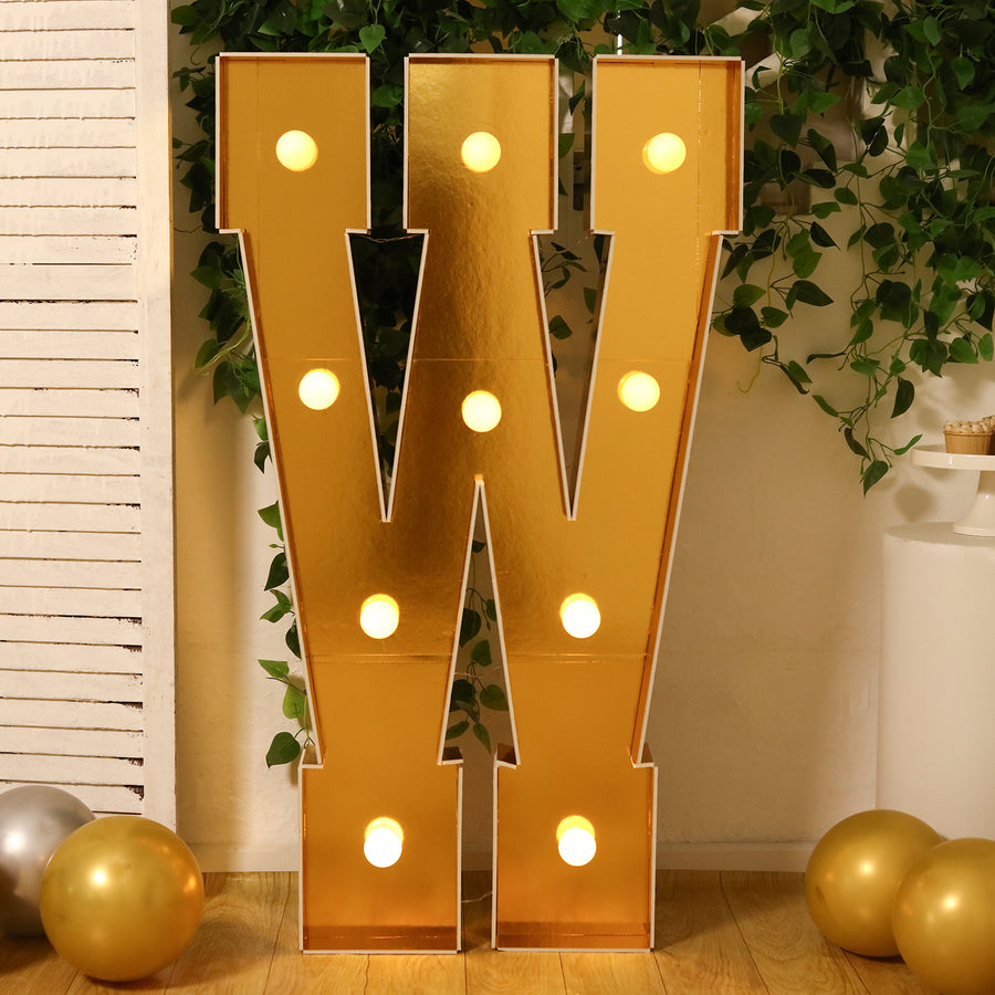 Gold marquee letter "W" with lights, set against a festive backdrop.