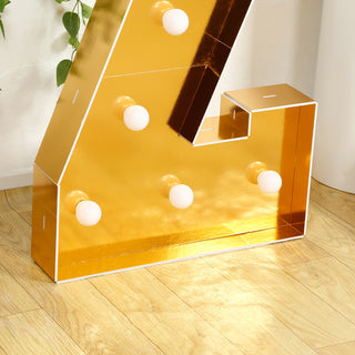 Gold marquee letter with bulbs on a wooden floor.