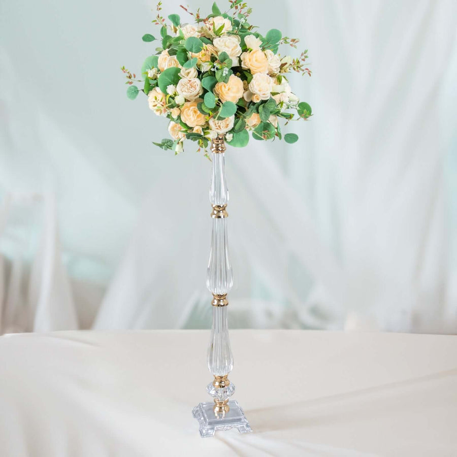 Elegant floral arrangement on a clear glass stand with soft greenery and cream roses.