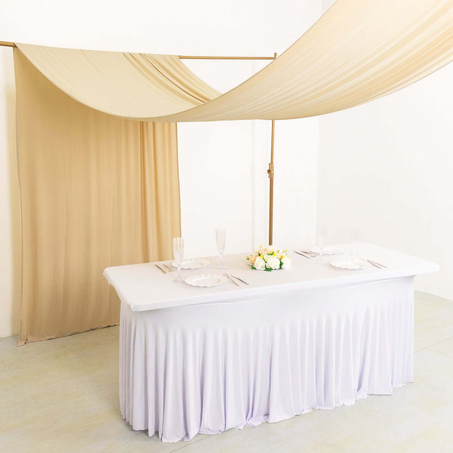 Elegant table setup with draped fabric and floral centerpiece in a studio setting.