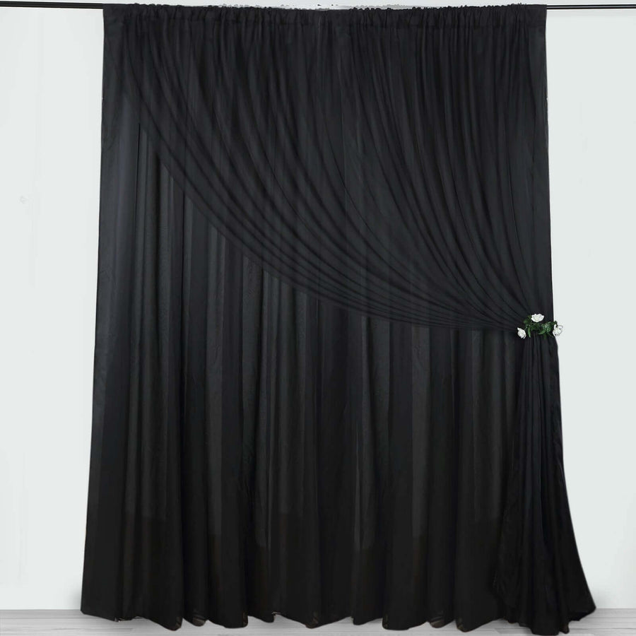 Elegant black curtain with draped design and floral tieback.