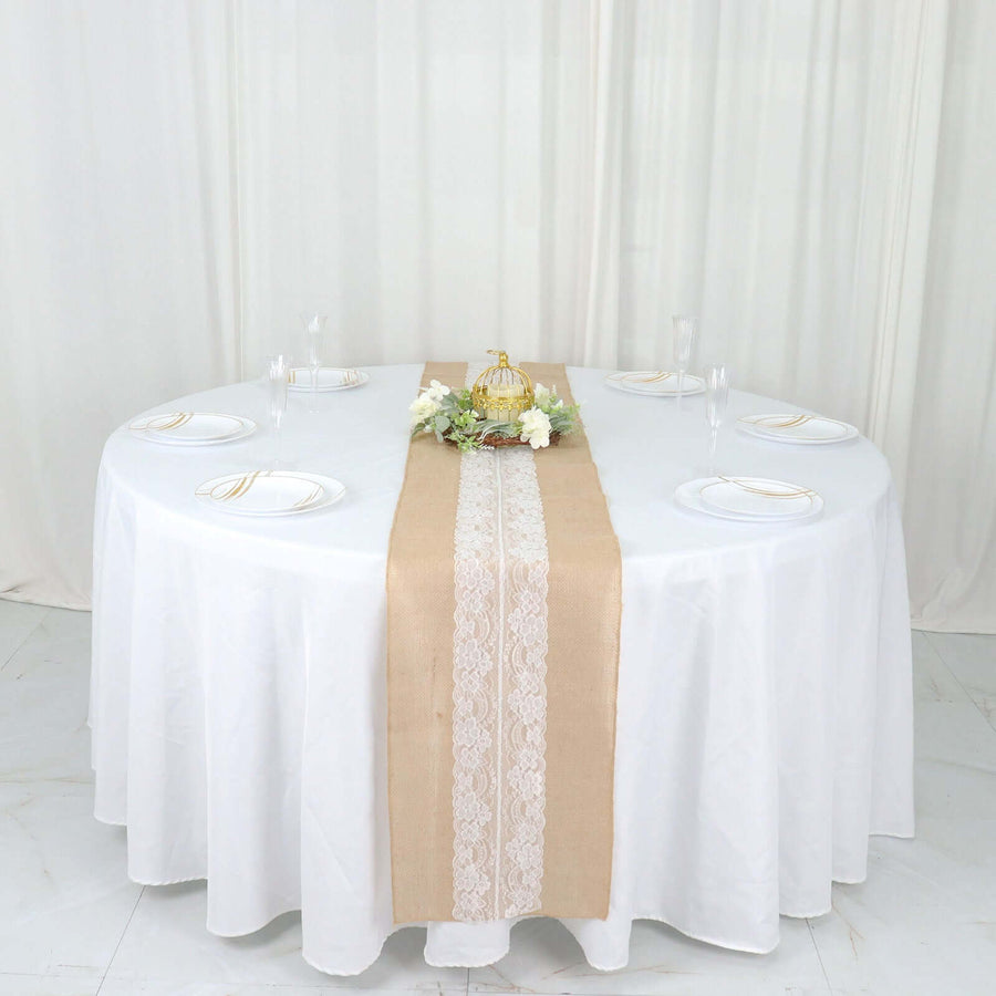 Elegant round table set with a white tablecloth and burlap runner adorned with flowers.