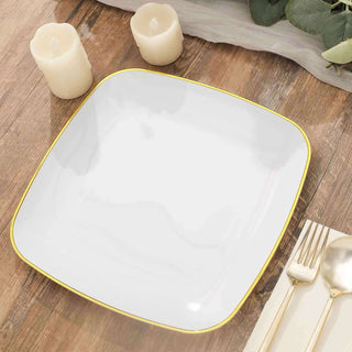 Elegant white square plate with gold rim, styled with candles and cutlery.