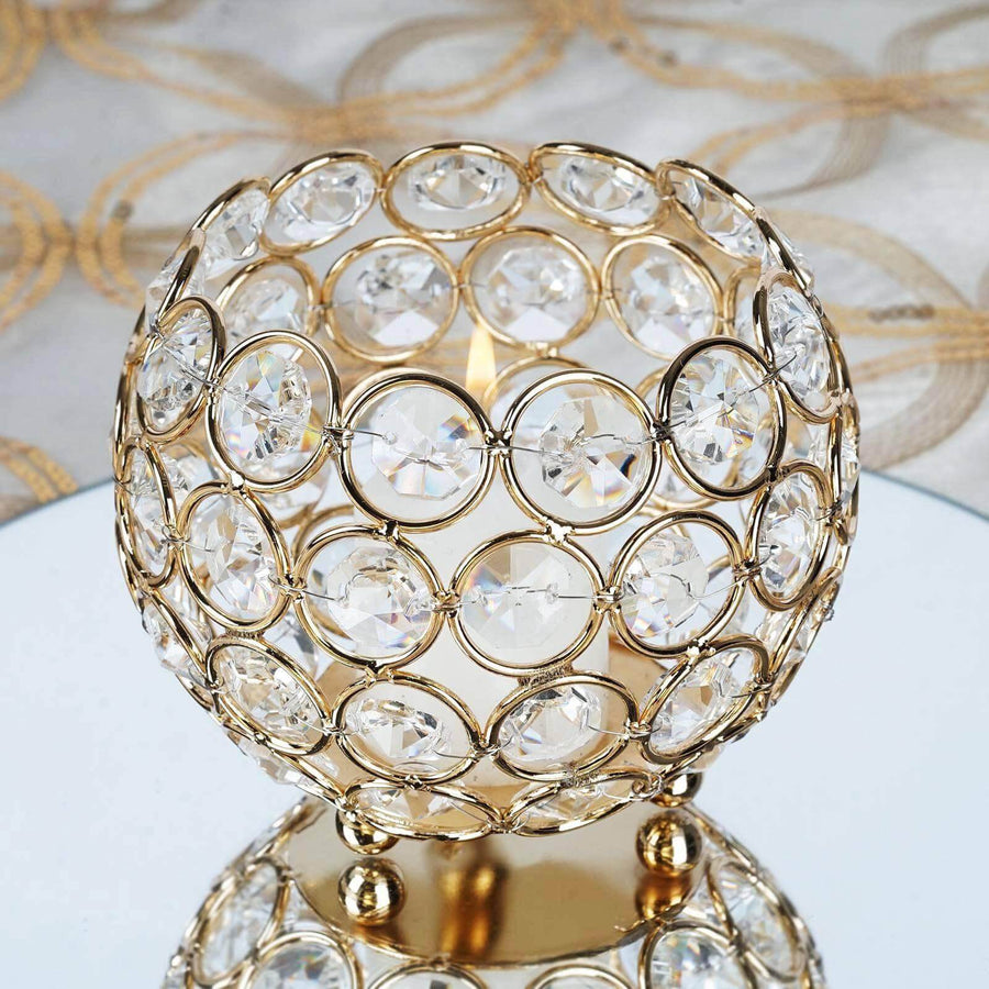 Elegant gold candle holder with crystal accents on a mirrored surface.