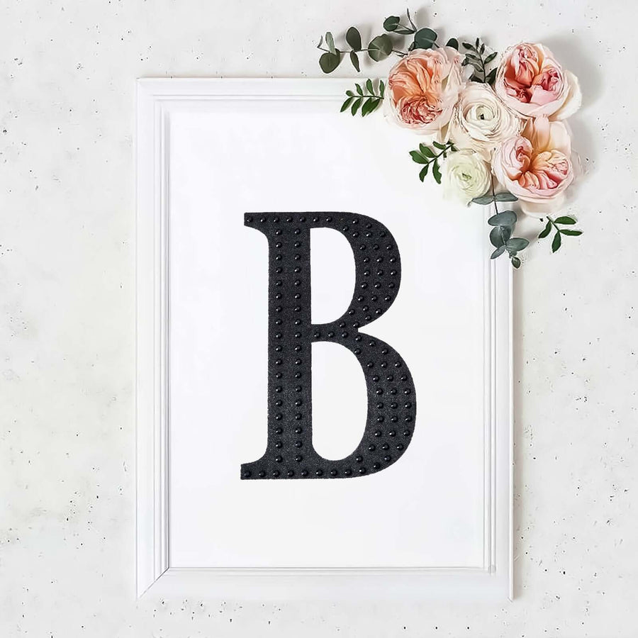 Black letter "B" framed with flowers on a white background.