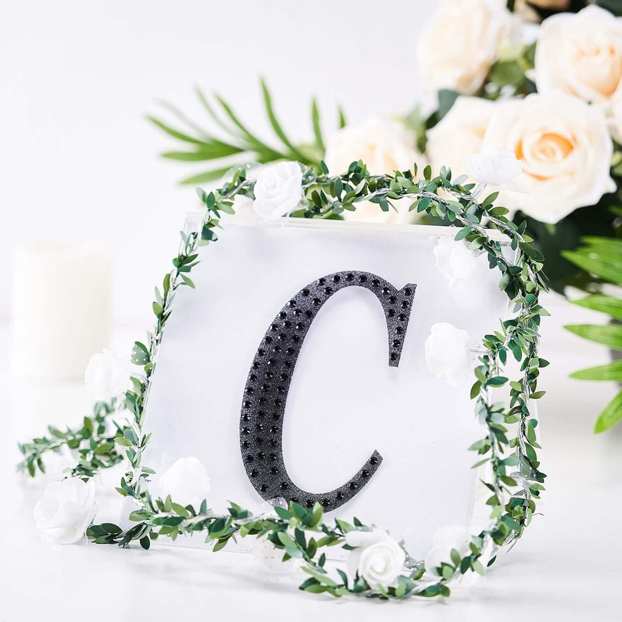 Decorative letter "C" with floral accents in a studio setting.