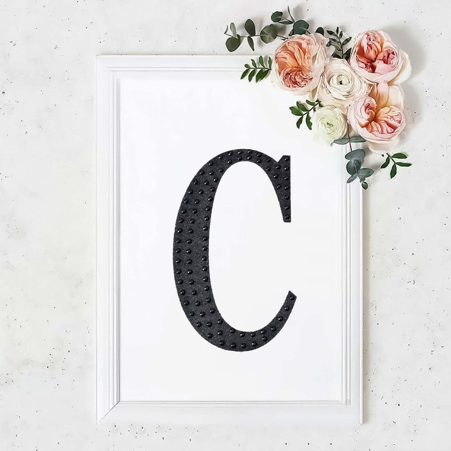 Framed letter 'C' with floral accents on a white background.