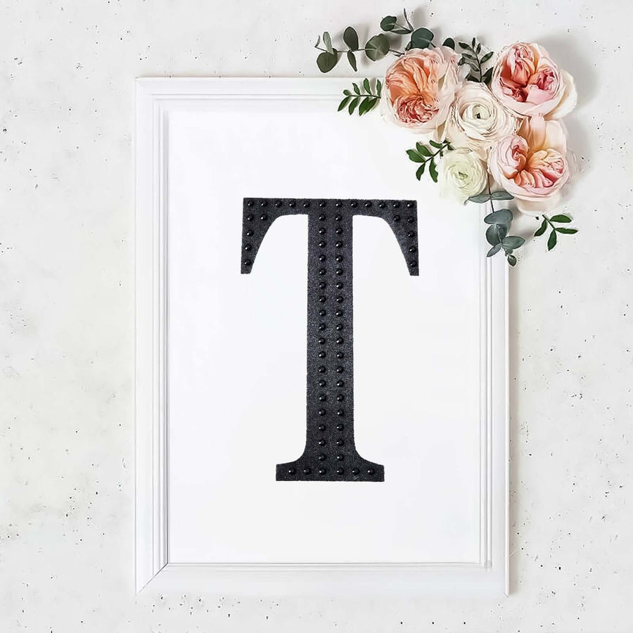 Black letter "T" framed art with flowers on a white background.