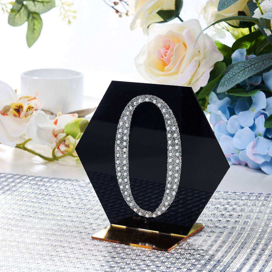 Black hexagon table number "0" with rhinestones on a decorative table setting.