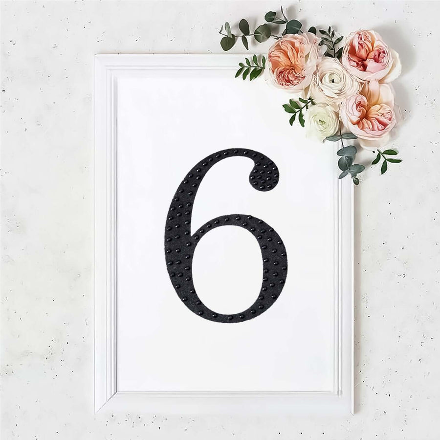 Black number six in a white frame with flowers, decorative wall art.