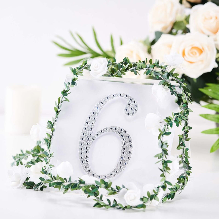Table number six adorned with greenery and flowers.