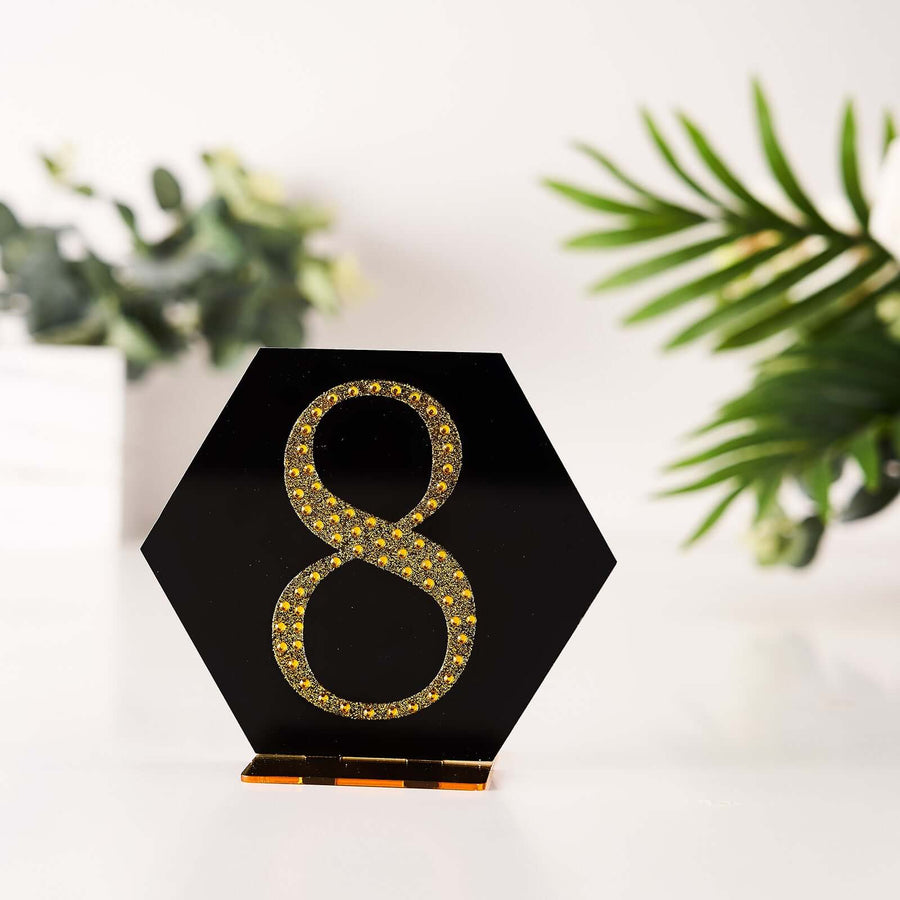 Black hexagon table number 8 with yellow rhinestones on a blurred background.