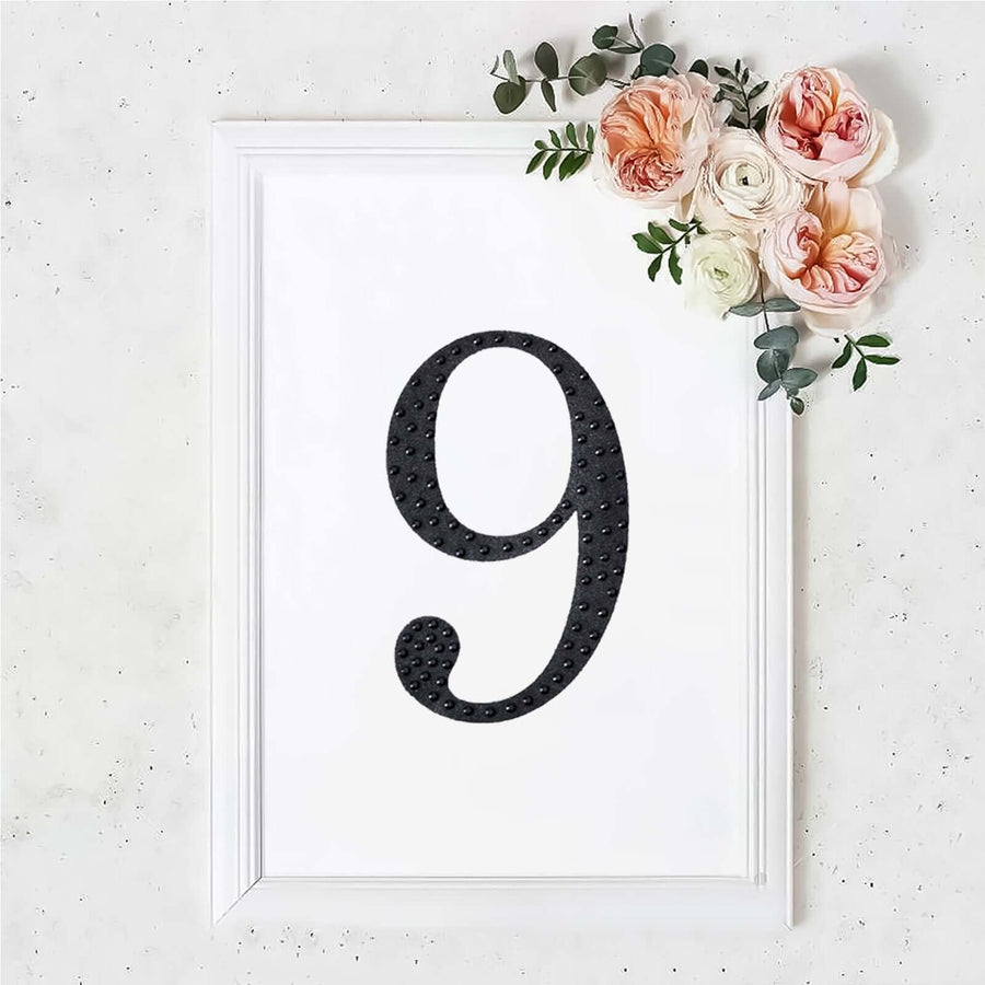 Black number 9 in a white frame with flowers on top.