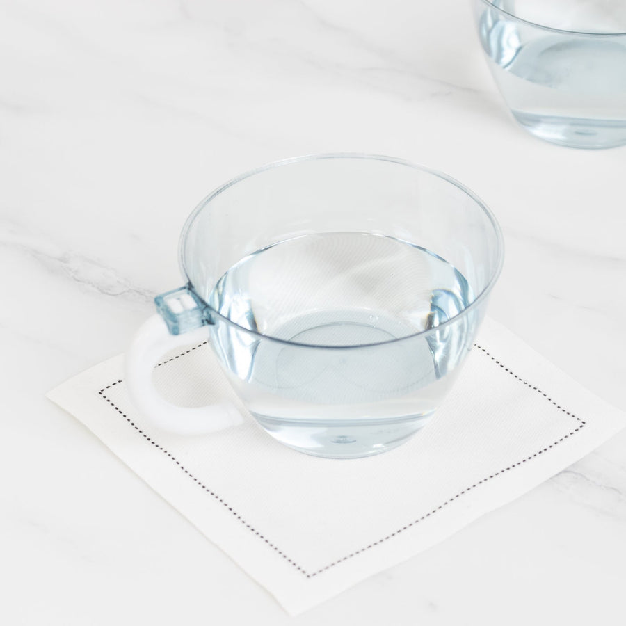 Clear glass cup with water on a white napkin.