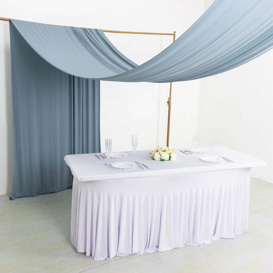 Elegant dining table setup with draped fabric backdrop and floral centerpiece