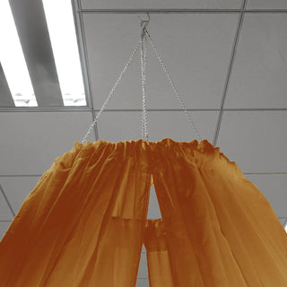 Orange fabric drapes hanging from a chain in a ceiling.