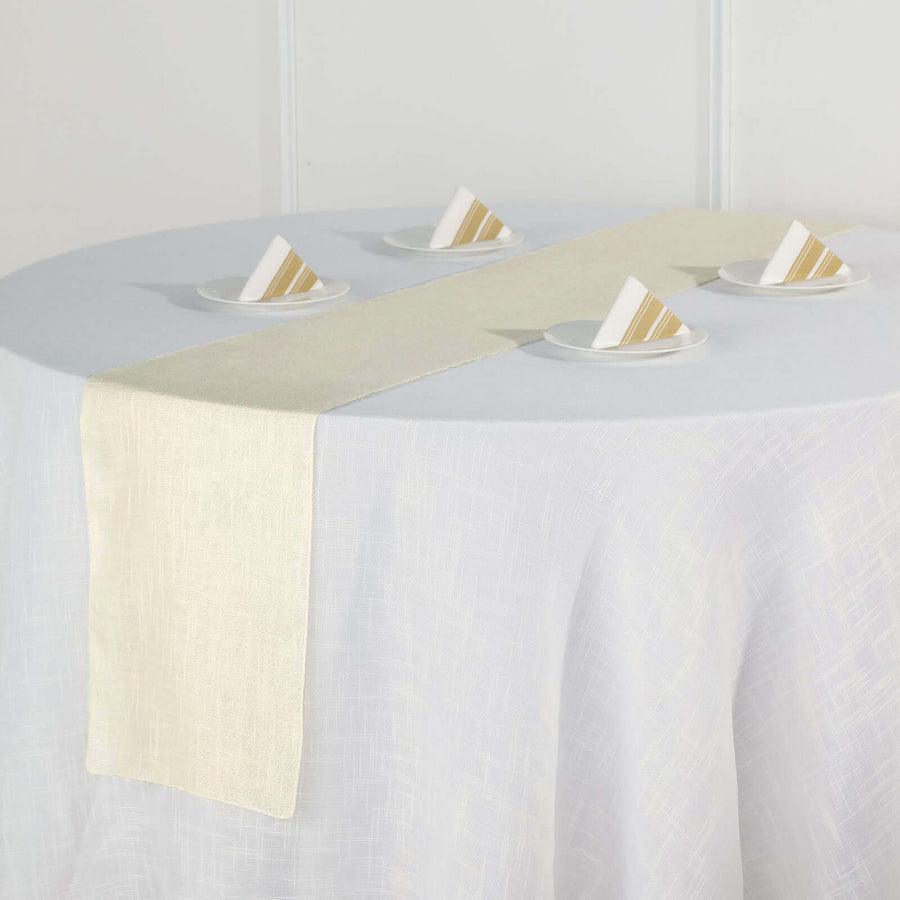 Cream table runner on a round table with folded napkins.