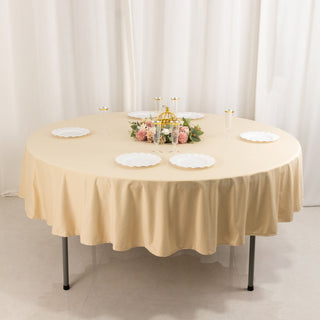 Round table set with beige tablecloth and elegant decorations.