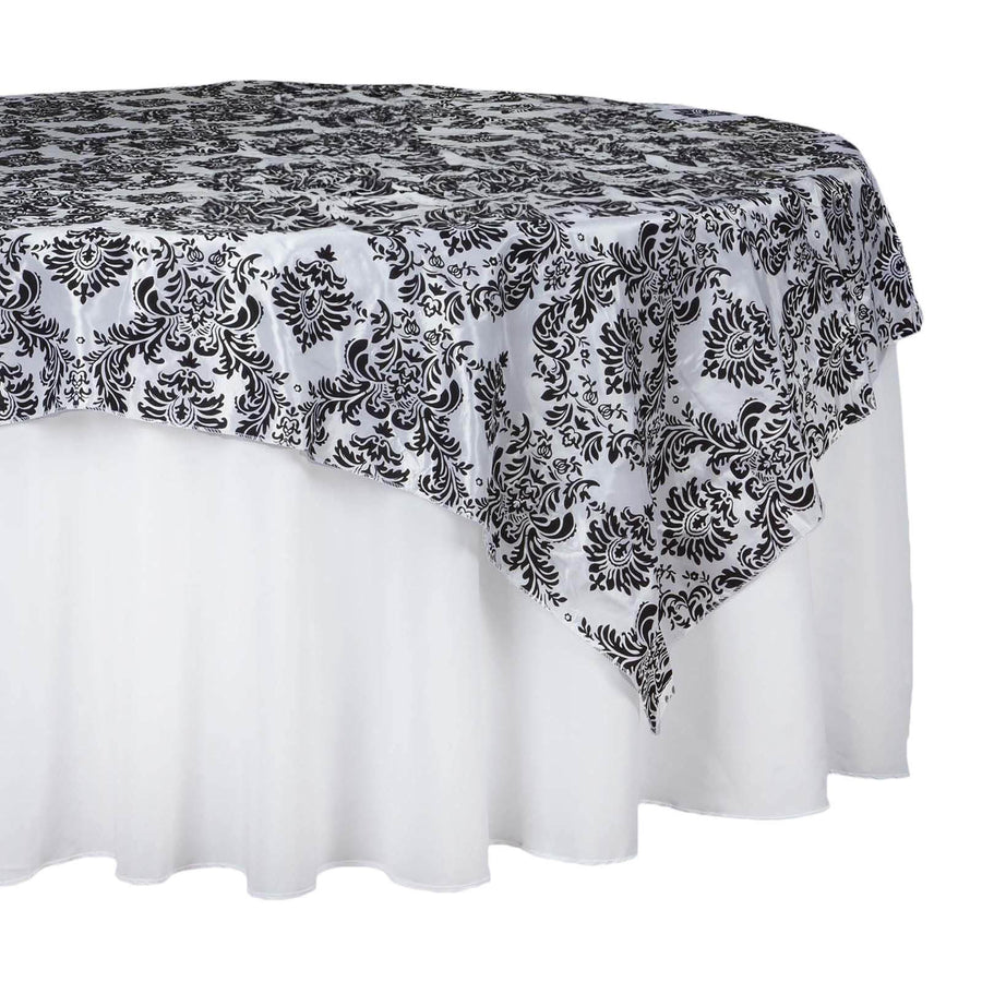Black and white damask tablecloth draped over a round table.