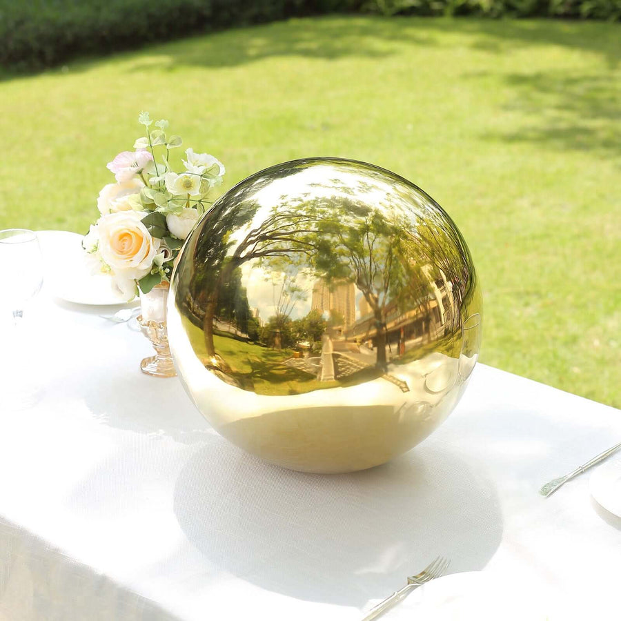 Gold decorative sphere on an outdoor table with flowers.
