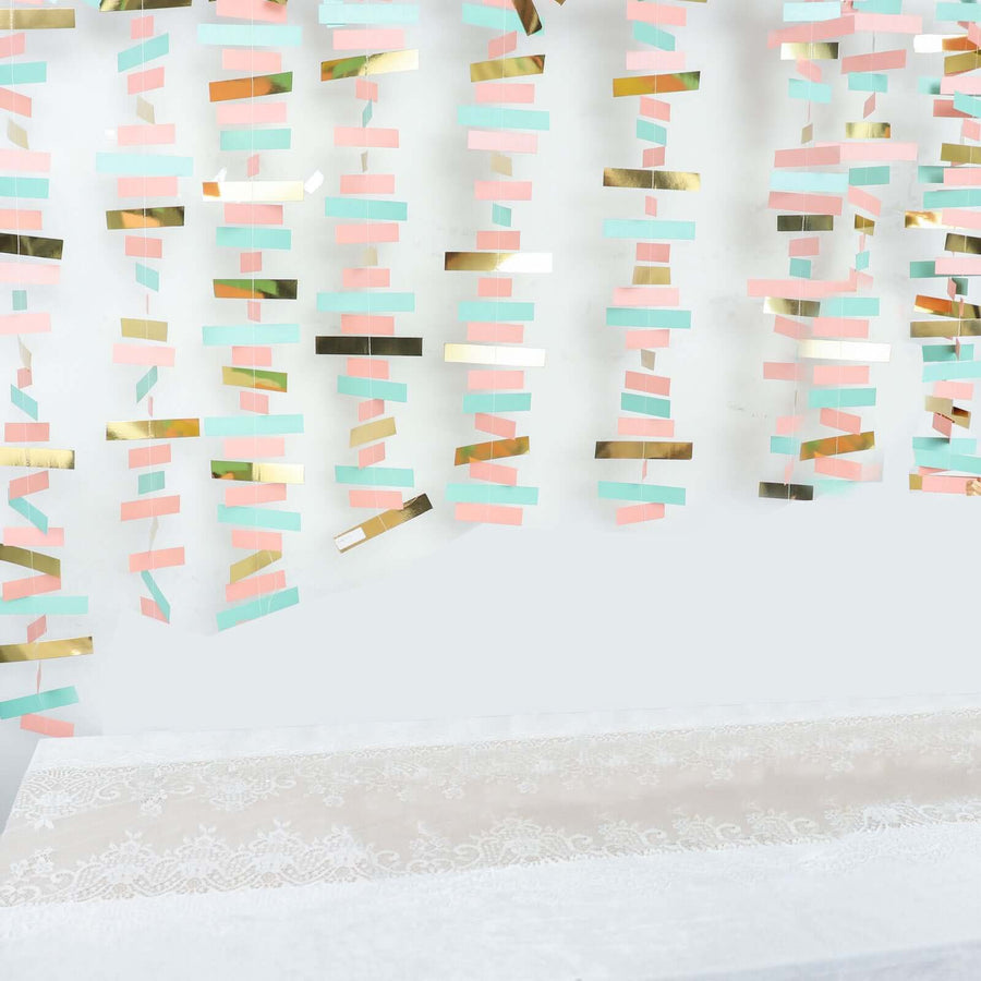 Colorful hanging decorations in pastel pink, mint, and gold against a plain background.