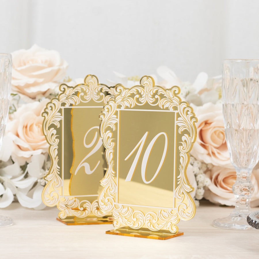 Elegant gold table numbers 2 and 10 with ornate design against a floral backdrop.