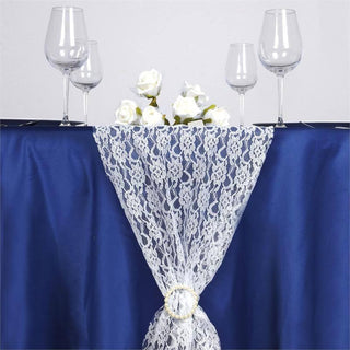 Elegant lace table skirt with decorative white roses and wine glasses.