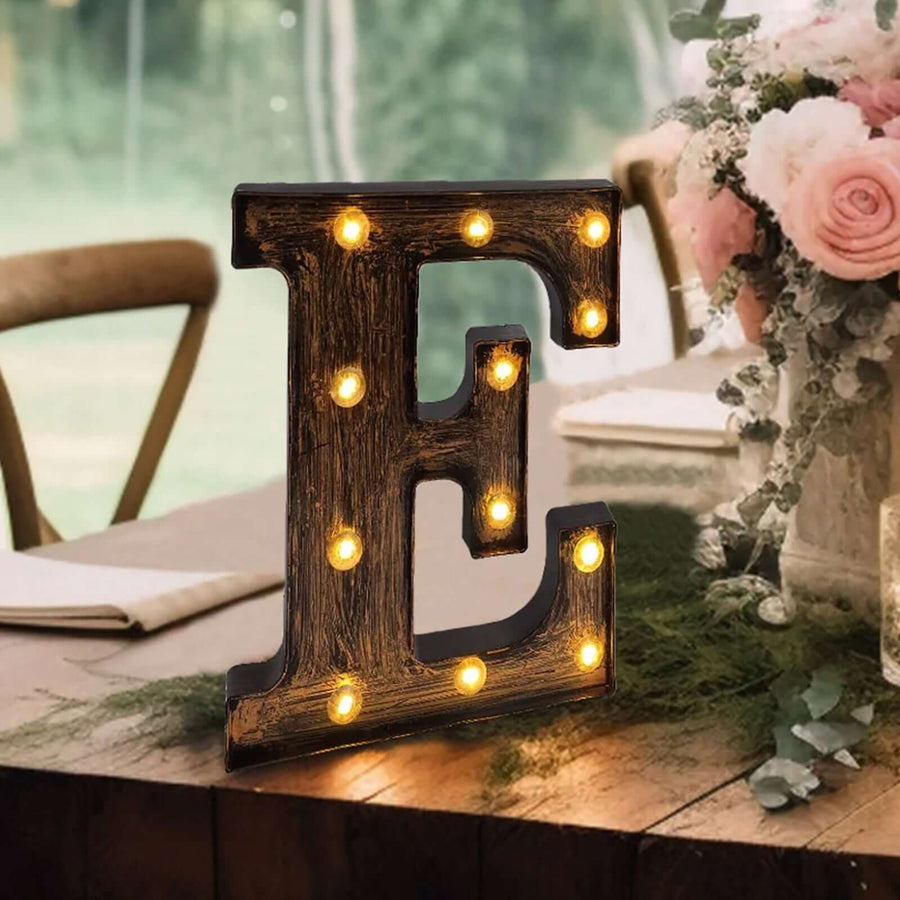 Decorative marquee letter 'E' with lights on a rustic table setting.