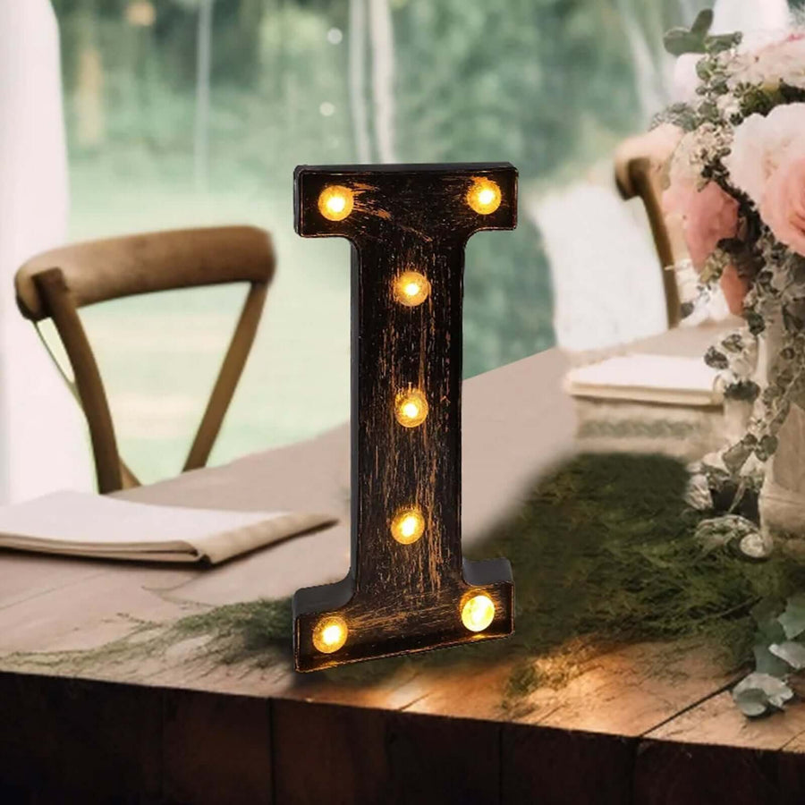 Decorative marquee letter "I" with lights on a rustic table setting.