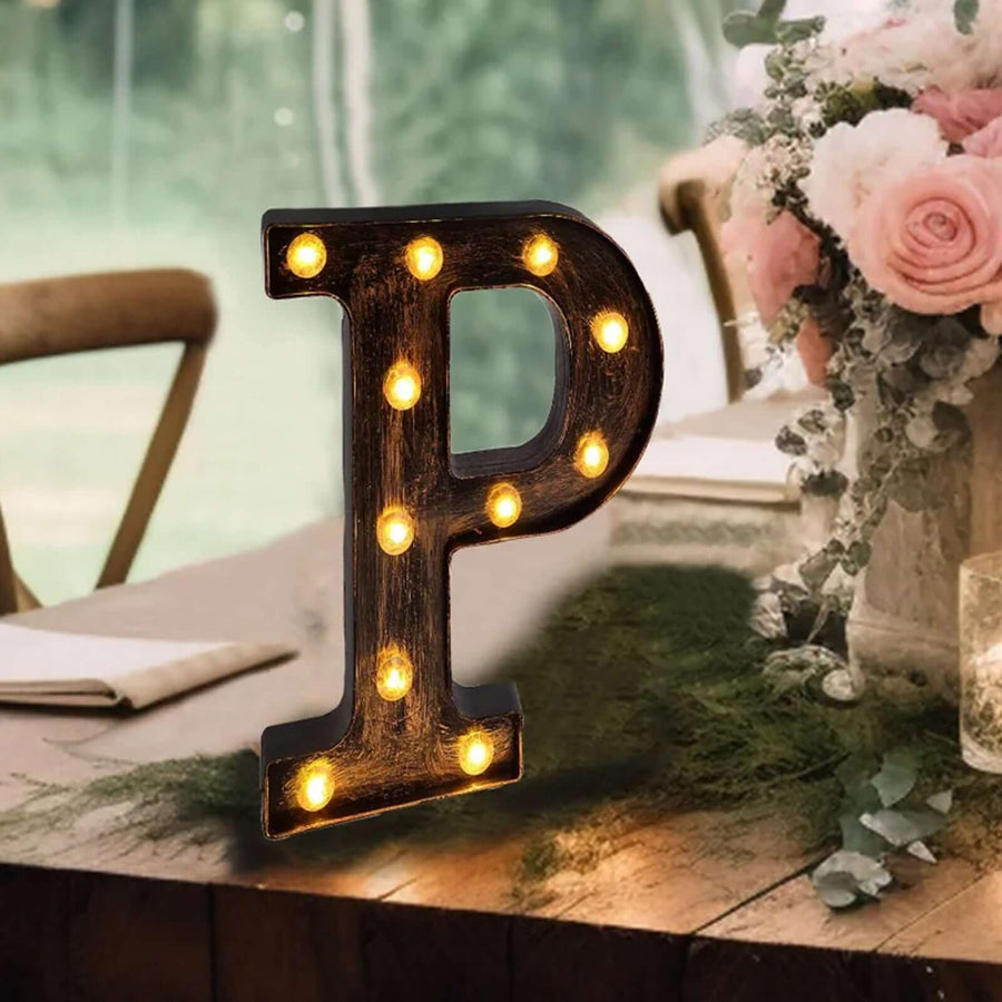 Decorative marquee letter "P" with lights on a rustic table setting.