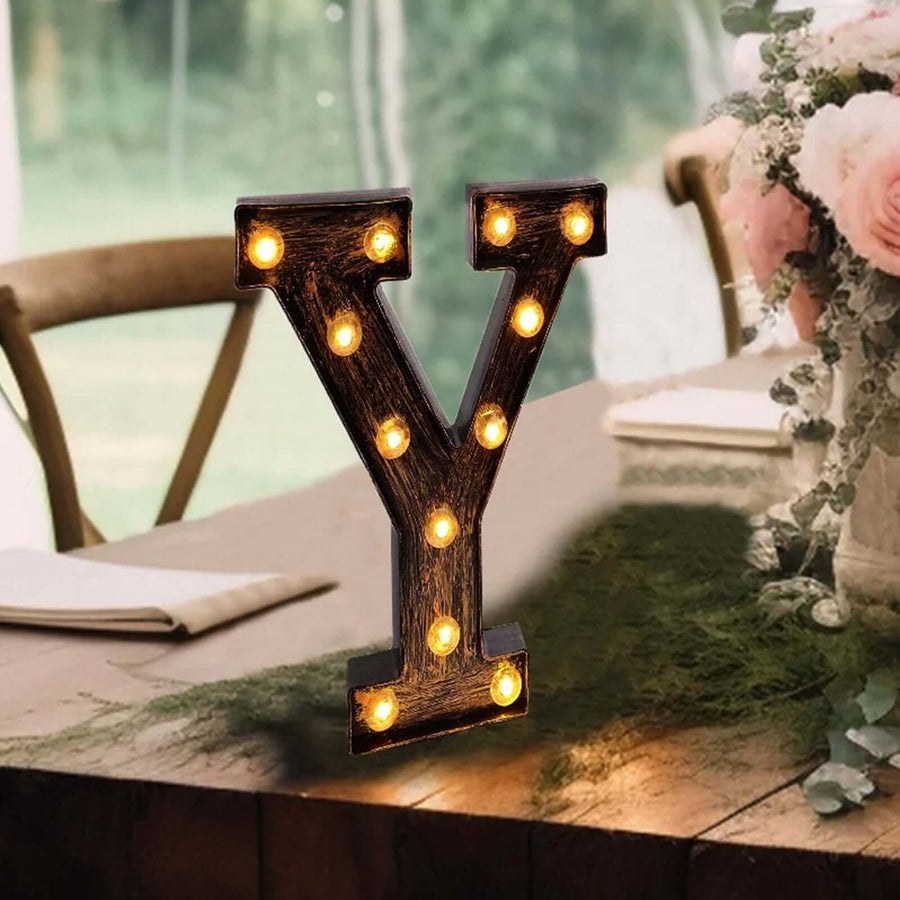 Vintage light-up letter 'Y' decoration on a table with floral backdrop.