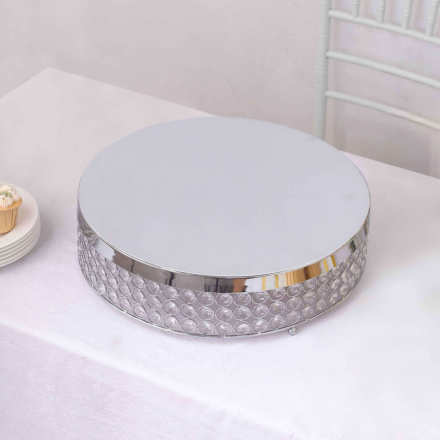Silver cake stand with crystal detailing on a white tablecloth.