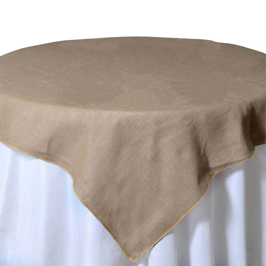 Round burlap tablecloth with a yellow trim on a white table.