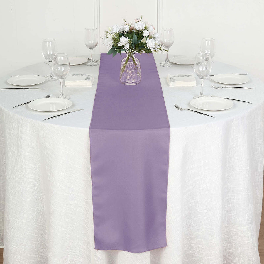 Purple table runner on a dining table set with plates and glasses.