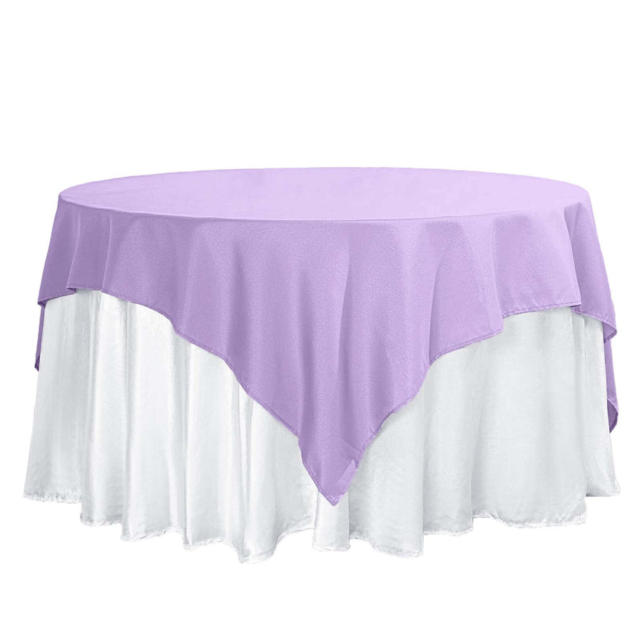Purple tablecloth draped over a round table with a white skirt.
