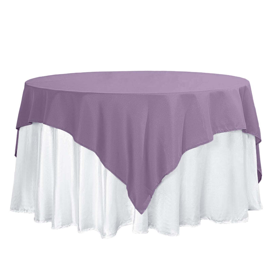 Purple tablecloth draped over a round table with white skirt