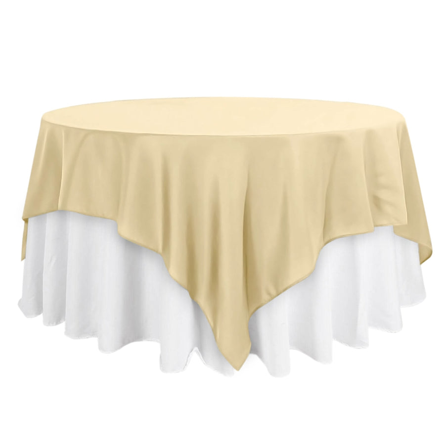 Round table with a beige tablecloth and white skirt.