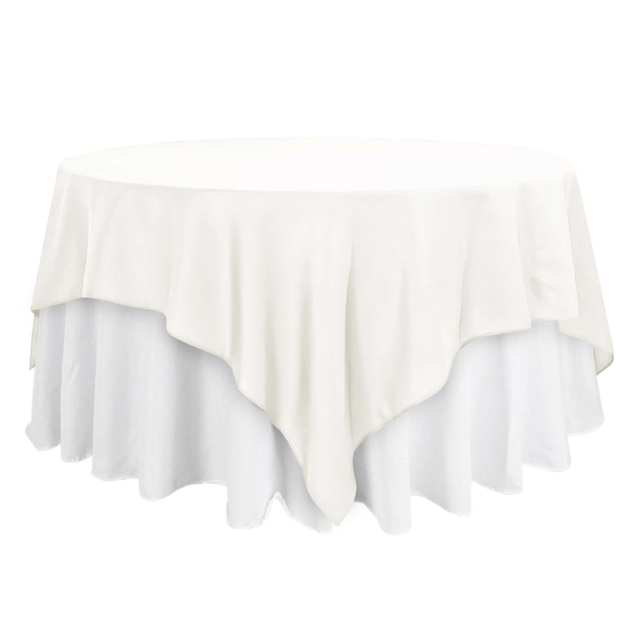 Round white tablecloth with elegant draping on a plain background
