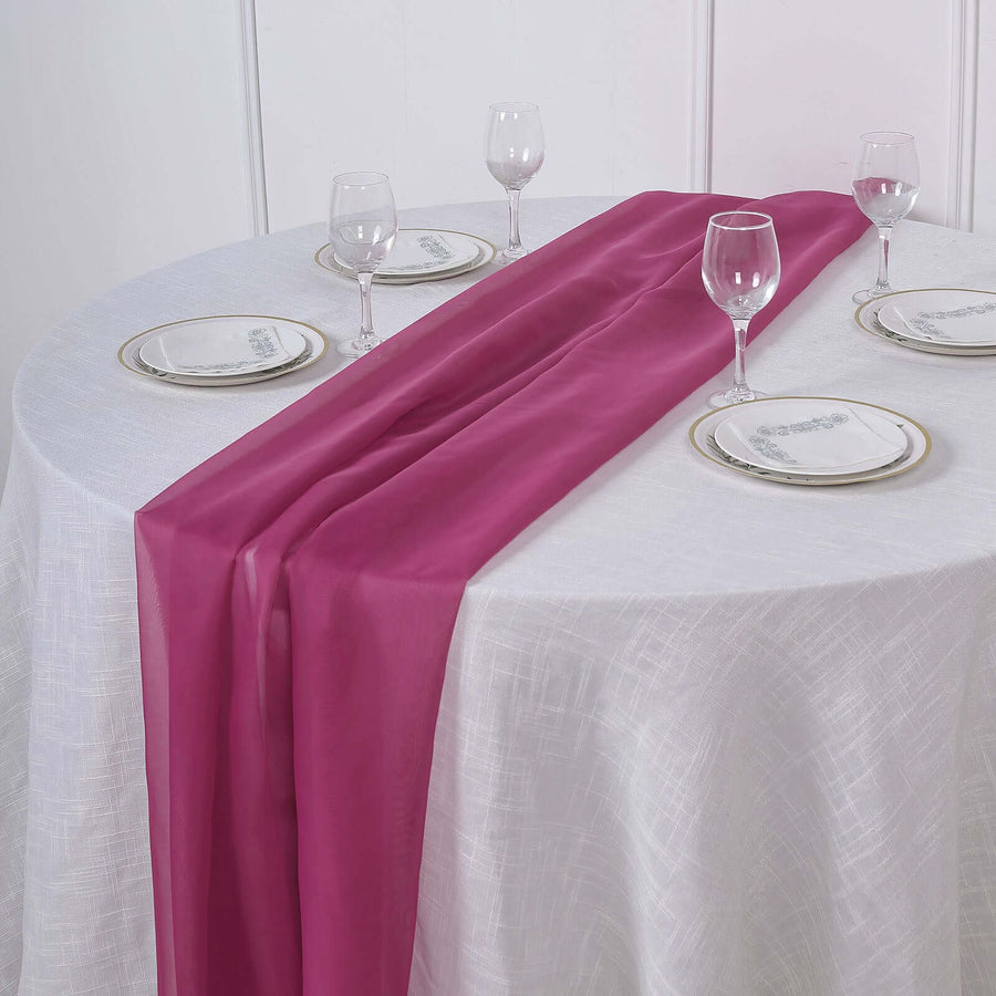 Elegant magenta table runner on a white tablecloth with dining setup.