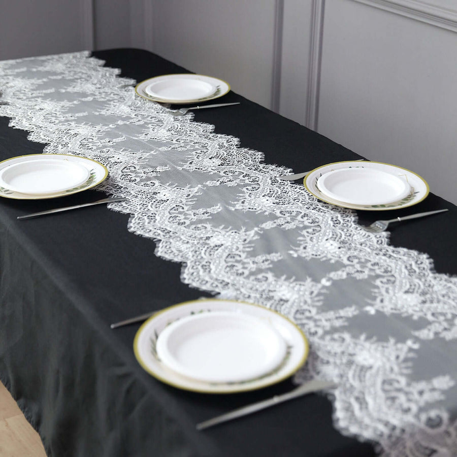 Lace table runner on a black table with white plates arranged elegantly.