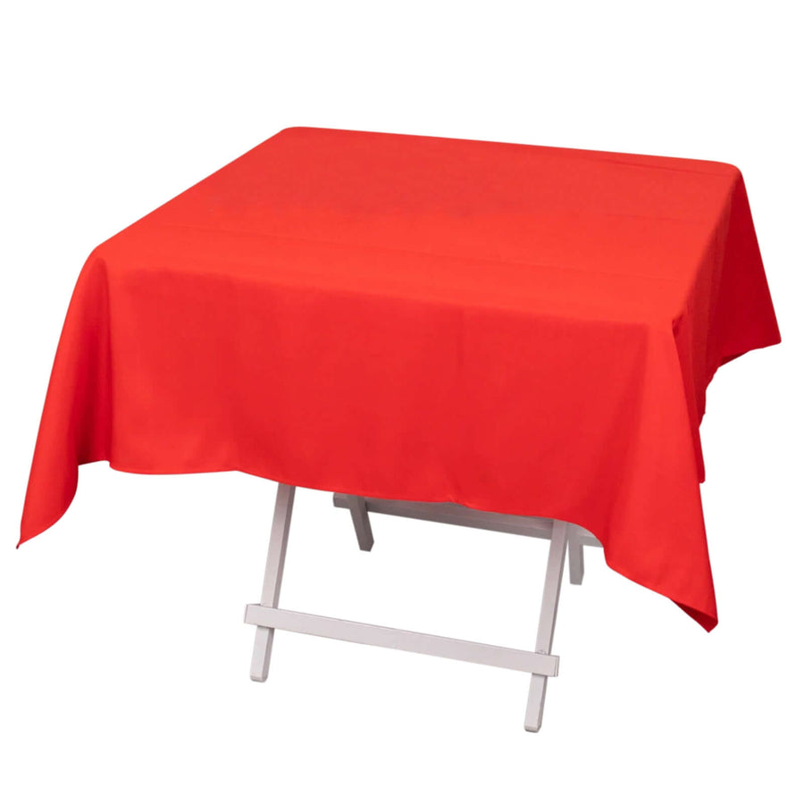 Red tablecloth draped over a folding table for dining.