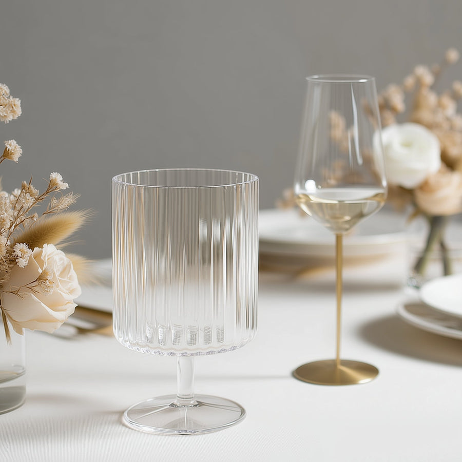 Elegant ribbed glassware set on a dining table with floral arrangements.