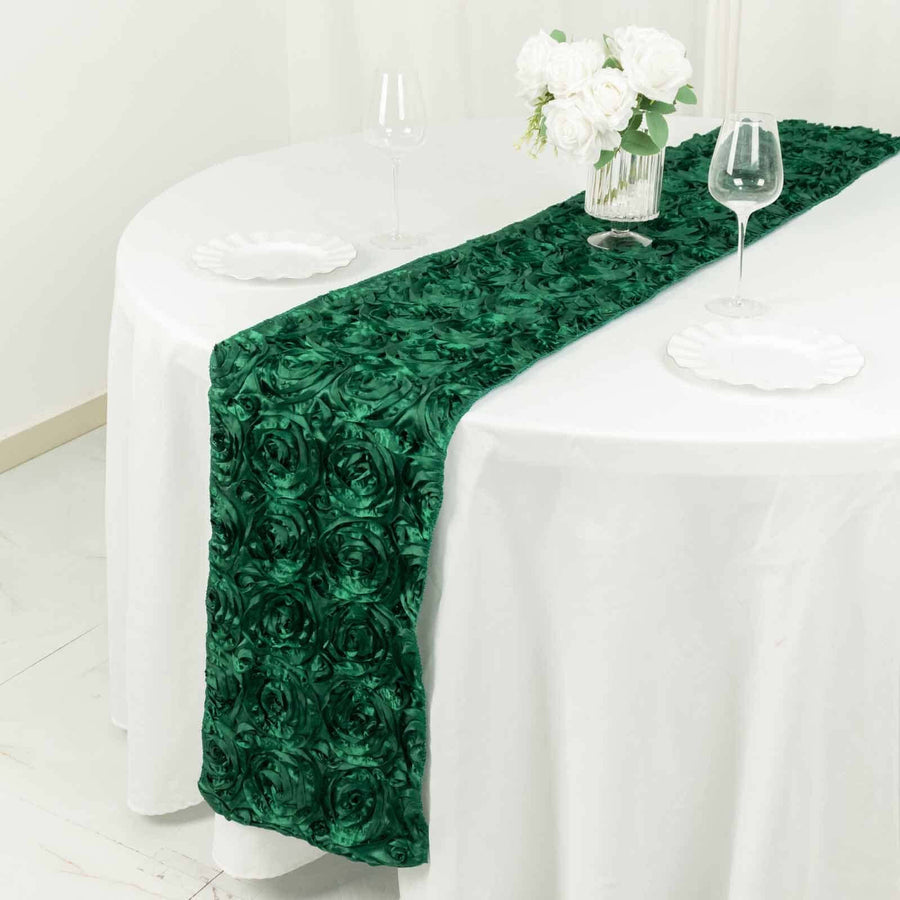 Green rose-patterned table runner on a white table with glassware and flowers.